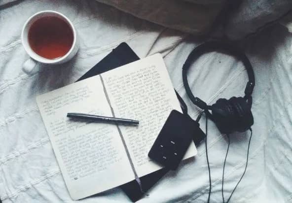 Writing journal with tea and noise-cancelling headphones